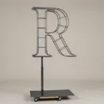 Monogram letter R topiary frame in Cinzel style, bare galvanized steel on an adjustable stand
