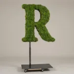 Monogram letter R topiary in Cinzel style, packed with green moss, on an adjustable stand