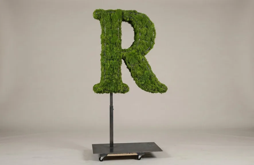 Monogram letter R topiary in Cinzel style, packed with green moss, on an adjustable stand