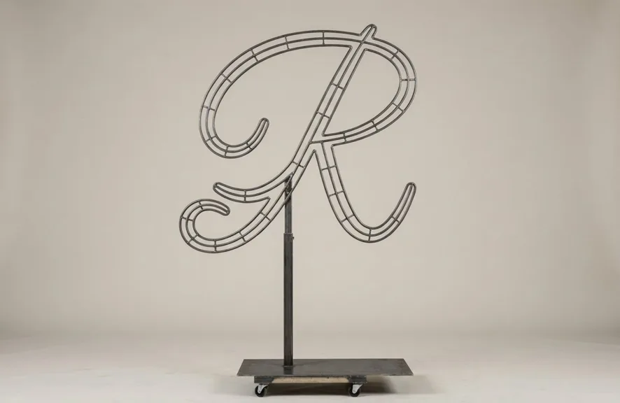 Monogram letter R topiary frame in Flowing script style, bare galvanized steel on an adjustable stand