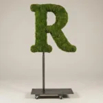 Monogram letter R topiary in Roman style, packed with green moss, on an adjustable stand