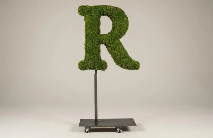 Monogram letter R topiary in Roman style, packed with green moss, on an adjustable stand