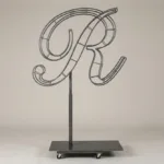 Monogram letter R topiary frame in Script style, bare galvanized steel on an adjustable stand