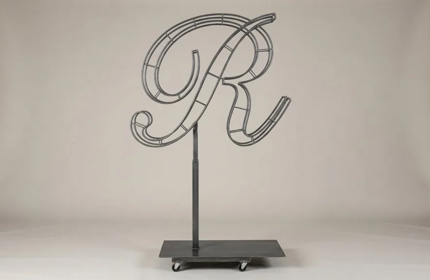 Monogram letter R topiary frame in Script style, bare galvanized steel on an adjustable stand