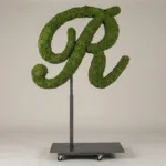 Monogram letter R topiary in Script style, packed with green moss, on an adjustable stand