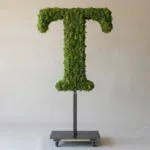 Monogram letter T topiary in Cinzel style, packed with green moss, on an adjustable stand