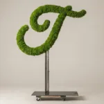 Monogram letter T topiary in Flowing script style, packed with green moss, on an adjustable stand