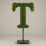 Monogram letter T topiary in Roman style, packed with green moss, on an adjustable stand