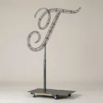 Monogram letter T topiary frame in Script style, bare galvanized steel on an adjustable stand