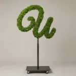 Monogram letter U topiary in Flowing script style, packed with green moss, on an adjustable stand