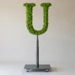 Monogram letter U topiary in Roman style, packed with green moss, on an adjustable stand