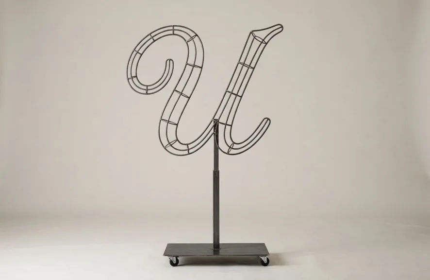 Monogram letter U topiary frame in Script style, bare galvanized steel on an adjustable stand