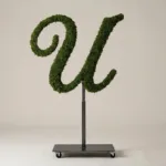 Monogram letter U topiary in Script style, packed with green moss, on an adjustable stand