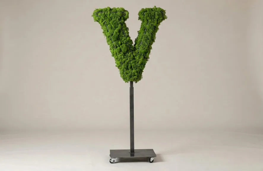 Monogram letter V topiary in Cinzel style, packed with green moss, on an adjustable stand