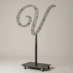 Monogram letter V topiary frame in Flowing script style, bare galvanized steel on an adjustable stand