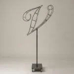 Monogram letter V topiary frame in Script style, bare galvanized steel on an adjustable stand