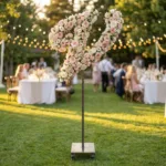 Monogram letter V topiary covered in flowers as a photo backdrop at a garden wedding