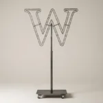Monogram letter W topiary frame in Cinzel style, bare galvanized steel on an adjustable stand