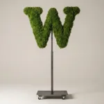 Monogram letter W topiary in Cinzel style, packed with green moss, on an adjustable stand