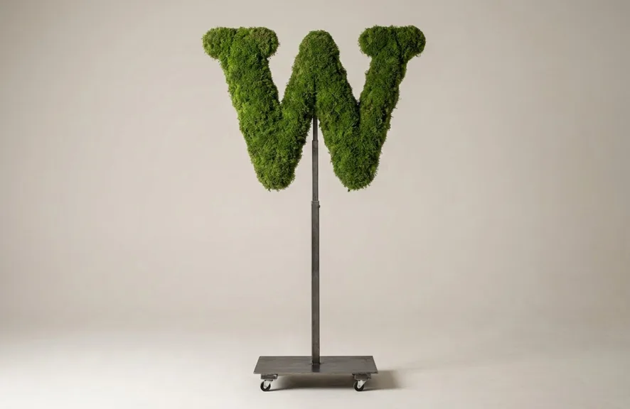 Monogram letter W topiary in Cinzel style, packed with green moss, on an adjustable stand