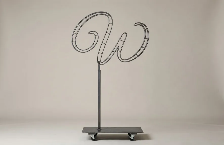 Monogram letter W topiary frame in Flowing script style, bare galvanized steel on an adjustable stand