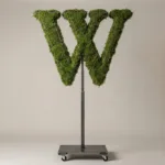 Monogram letter W topiary in Roman style, packed with green moss, on an adjustable stand