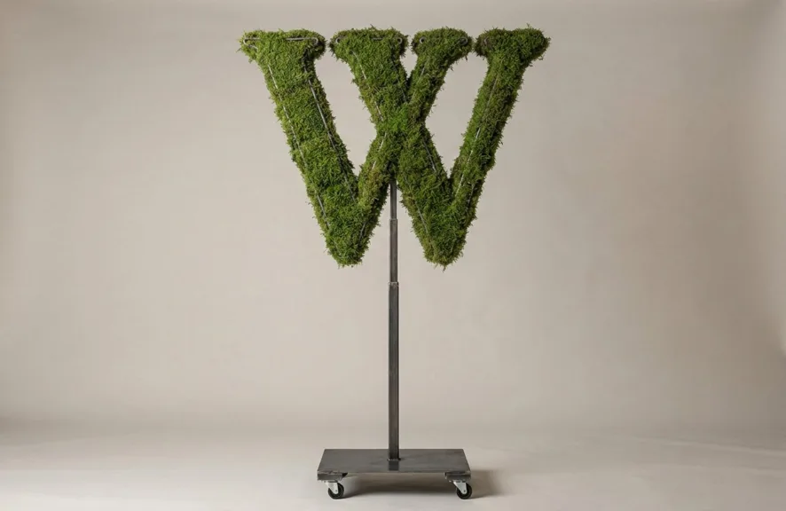 Monogram letter W topiary in Roman style, packed with green moss, on an adjustable stand