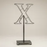 Monogram letter X topiary frame in Cinzel style, bare galvanized steel on an adjustable stand