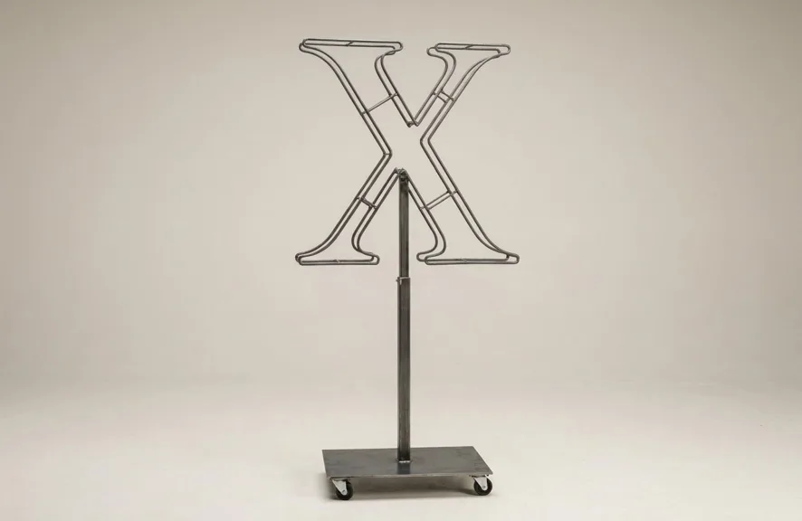 Monogram letter X topiary frame in Cinzel style, bare galvanized steel on an adjustable stand