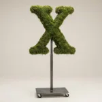Monogram letter X topiary in Cinzel style, packed with green moss, on an adjustable stand