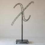 Monogram letter X topiary frame in Flowing script style, bare galvanized steel on an adjustable stand