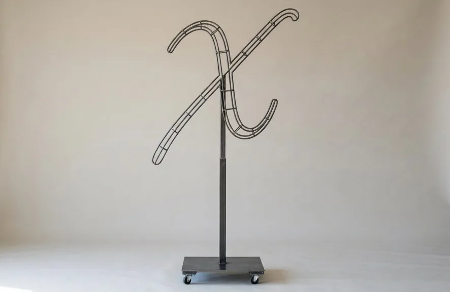 Monogram letter X topiary frame in Flowing script style, bare galvanized steel on an adjustable stand