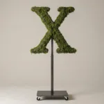 Monogram letter X topiary in Roman style, packed with green moss, on an adjustable stand