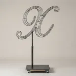 Monogram letter X topiary frame in Script style, bare galvanized steel on an adjustable stand