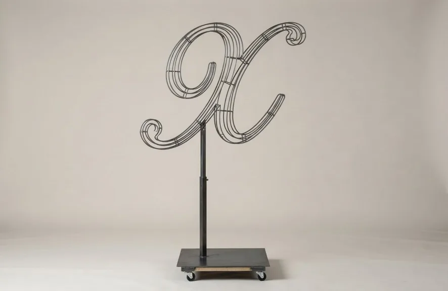 Monogram letter X topiary frame in Script style, bare galvanized steel on an adjustable stand