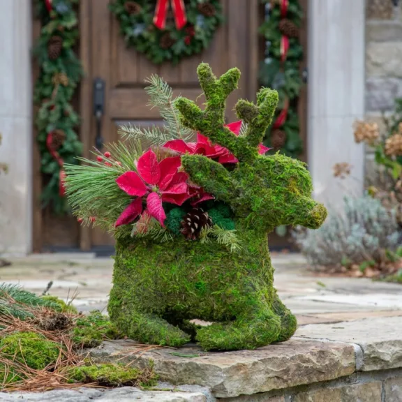 Moss reindeer planter on a stone step at a shop entrance with evergreen garland